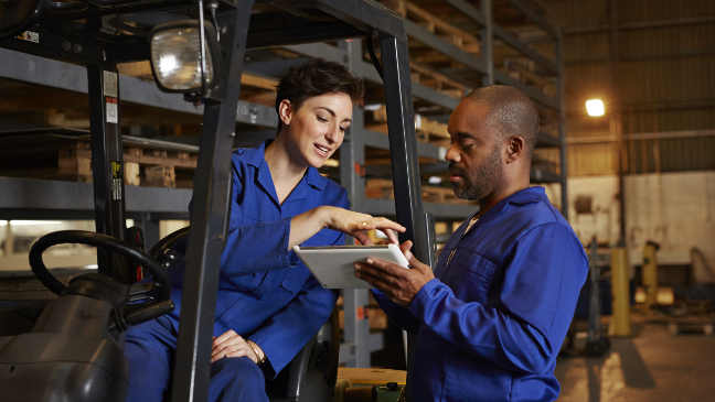 Two employees looking at a clipboard in a warehouse setting